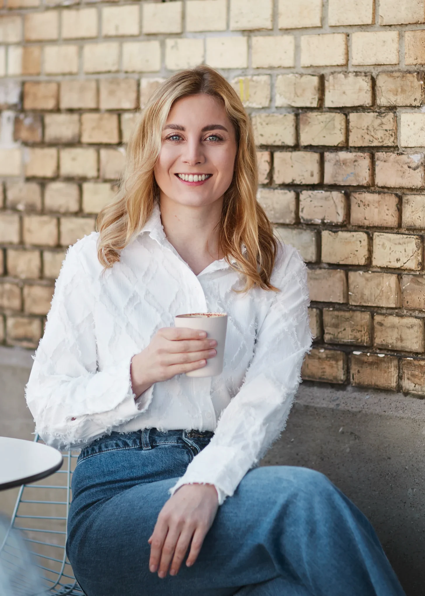 Person am Cafe trinken sitzt vor einer Wand an einem Tisch